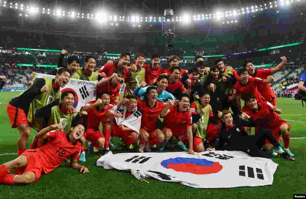 Los jugadores de Corea del Sur posan con su bandera, tras vencer a Portugal 2-1, y clasificarse a la siguiente etapa de la Copa Mundial.