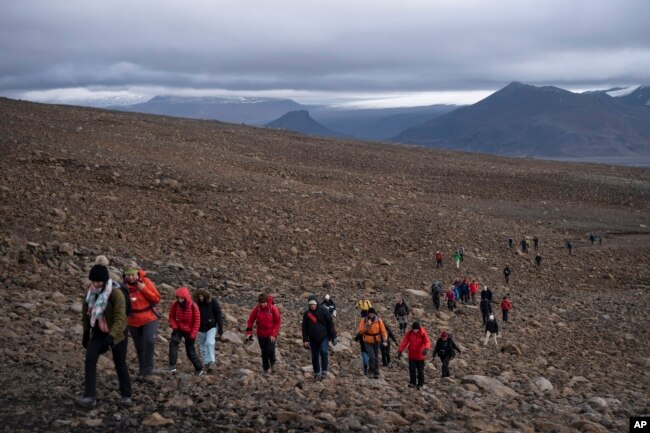 In this file photo, people climb to the top of what once was the Okjokull glacier, in Iceland, Sunday, Aug. 18, 2019. (AP Photo/Felipe Dana, File)