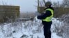 Un oficial de policía se encuentra junto a una parte de un misil de crucero ruso derribado por las Fuerzas de Defensa Aérea de Ucrania, en medio del ataque de Rusia a Ucrania, en la región de Kyiv, Ucrania, el 16 de diciembre de 2022.