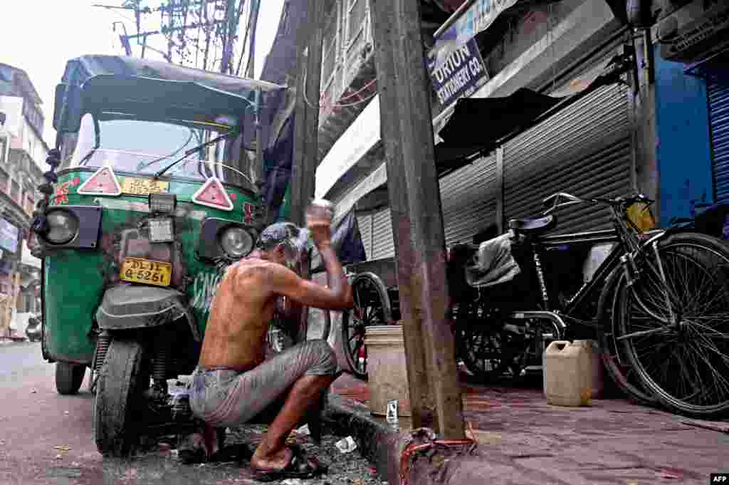 Qishning sovuq kunida tashqarida, yo&#39;lning chetida yuvinayotgan odam. Dehli, Hindiston.&nbsp;