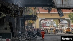 Rescuers gather in front of the Grand Diamond hotel-casino after a deadly fire broke out, in Poipet near the Thailand border, Cambodia.