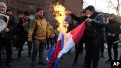 Iranian demonstrators set fire to French flags during their gathering to protest against the publication of caricatures of Iran's Supreme Leader Ayatollah Ali Khamenei in the French satirical magazine Charlie Hebdo, in front of the French Embassy in Tehran, Iran, Jan. 8, 2023.