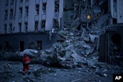An emergency worker walks in front of a damaged hotel following a Russian attack in Kyiv, Ukraine, Dec. 31, 2022.