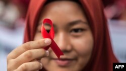 FILE - Seorang pelajar Indonesia memegang pita merah sebagai bagian dari acara kesadaran pada peringatan Hari AIDS Sedunia di Medan, provinsi Sumatera Utara, 2 Desember 2018. -(Albert Ivan Damanik/AFP)