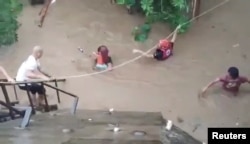 A rescuer helps people affected by floods in Gingoog city, Philippines, Dec. 25, 2022, in this screen grab obtained from a social media video. (Philippine Red Cross/Twitter/via Reuters)
