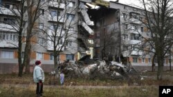 A woman passes by an apartment building damaged following by Russian shelling in Bakhmut, the site of the heaviest battles with the Russian troops, in the Donetsk region, Ukraine, Dec. 11, 2022. 