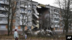 A woman passes by an apartment building damaged following by Russian shelling in Bakhmut, the site of the heaviest battles with the Russian troops, in the Donetsk region, Ukraine, Dec. 11, 2022. 