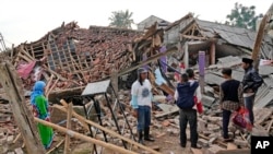 Warga mengamati reruntuhan rumah mereka yang rusak parah akibat gempa Senin di Cianjur, Jawa Barat, Selasa, 22 November 2022. (AP/Tatan Syuflana)