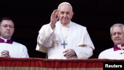 Pope Francis waves as he delivers his traditional Christmas Day Urbi et Orbi message to the city and the world from the main balcony of St. Peter's Basilica at the Vatican, Dec. 25, 2022. 