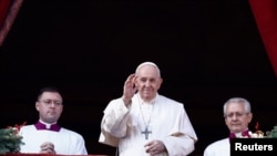 Pope Francis waves as he delivers his traditional Christmas Day Urbi et Orbi message to the city and the world from the main balcony of St. Peter's Basilica at the Vatican, Dec. 25, 2022. 