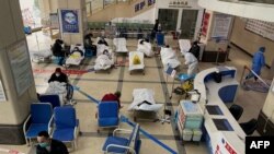 FILE - A man stands in front of a cordoned-off area, where Covid-19 coronavirus patients lie on hospital beds, in the lobby of the Chongqing No. 5 People's Hospital in China's southwestern city of Chongqing, Dec. 23, 2022.