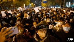 Protesters march along a street during a rally for the victims of a deadly fire as well as a protest against China's harsh COVID-19 restrictions in Beijing on Nov. 28, 2022. 