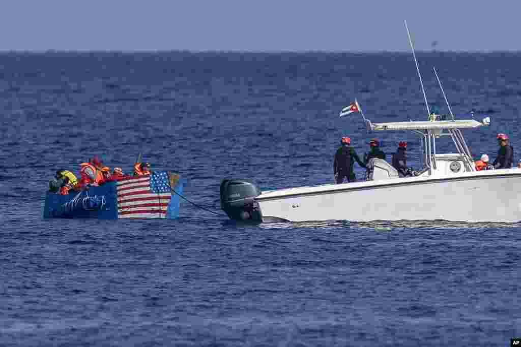 Луѓето во импровизиран брод со американското знаме насликано на страна се заробени од кубанската крајбрежна стража, видени од морскиот ѕид Малекон во Хавана.