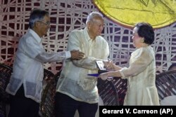 Bernadette Madrid dari Filipina, kanan, menerima penghargaannya oleh Aurelio Montinola, kiri, dan Ramon Magsaysay Jr., pada upacara Penghargaan Ramon Magsaysay di Manila pada Rabu, 30 November 2022. (Foto: AP/Gerard V. Carreon)