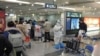 Passengers arriving on international flights wait in line next to a staff member wearing personal protective equipment (PPE) at the airport in Chengdu, China, Jan. 6, 2023. 