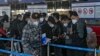 Masked travelers line up at the international flight check-in counter at Beijing Capital International Airport, in Beijing, China, Dec. 29, 2022.