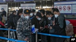 Masked travelers line up at the international flight check-in counter at Beijing Capital International Airport, in Beijing, China, Dec. 29, 2022.