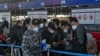 Pelancong mengenakan masker antre di konter check-in penerbangan internasional di Bandara Internasional Ibu kota Beijing, China, 29 Desember 2022.