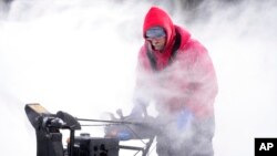 Mark Sorter clears snow from a downtown ice skating rink, Dec. 23, 2022, in Des Moines, Iowa.