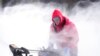 Mark Sorter clears snow from a downtown ice skating rink, Dec. 23, 2022, in Des Moines, Iowa.