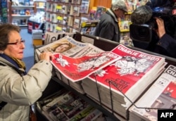 Seorang perempuan mengambil salinan majalah mingguan satir Prancis Charlie Hebdo di kios koran pada 25 Februari 2015, di Lille. (Foto: AFP)