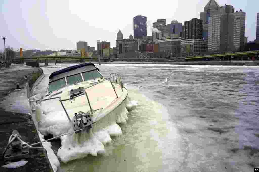 A boat lies partly underwater, surrounded by ice in the Allegheny River in downtown Pittsburgh, Pennsylvania, Dec. 26, 2022.