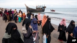 FILE - Ethnic Rohingya refugees walk to a temporary shelter after they landed on their wooden boat in North Aceh, Indonesia, Nov. 16, 2022.