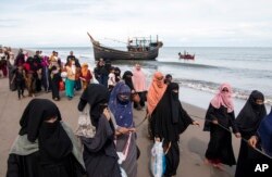 Warga etnis Rohingya berjalan menuju tempat penampungan sementara setelah mereka mendarat di perahu kayu mereka di Aceh Utara, 16 November 2022. (Foto: AP)