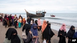 Ethnic Rohingya people walk to a temporary shelter after they landed on their wooden boat in North Aceh, Indonesia, Nov. 16, 2022.