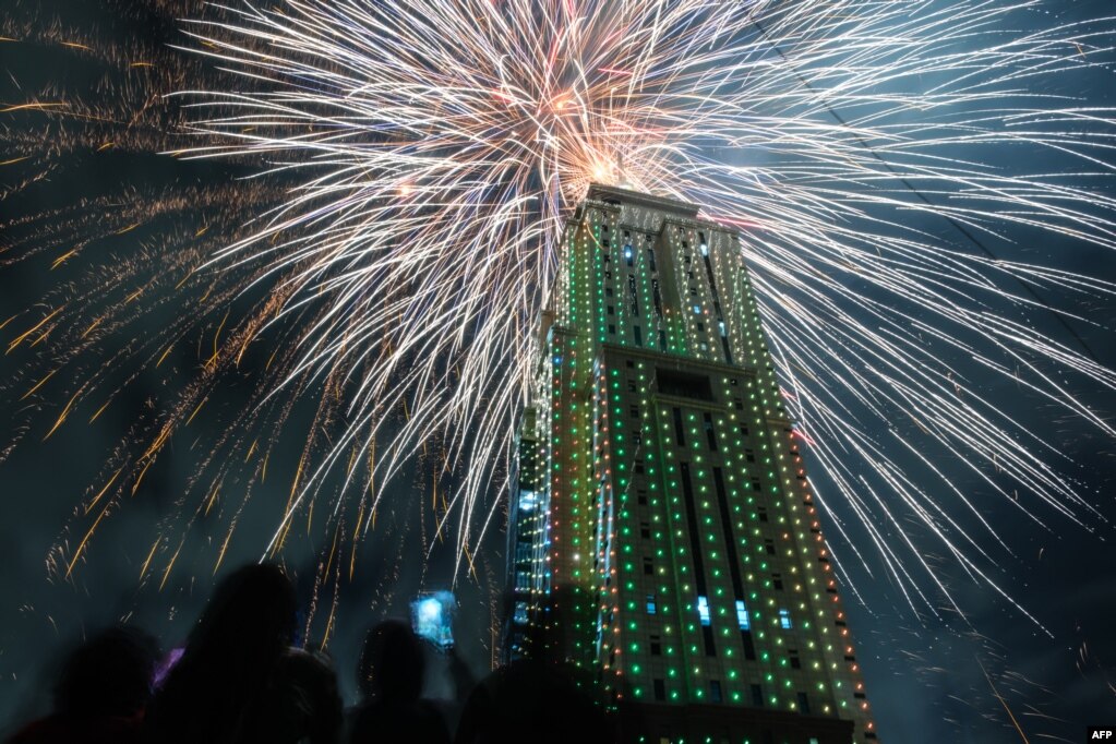 La gente mira el lanzamiento de fuegos artificiales desde el edificio de Old Mutual Tower para celebrar el año nuevo en Nairobi el 1 de enero de 2023. [AFP]