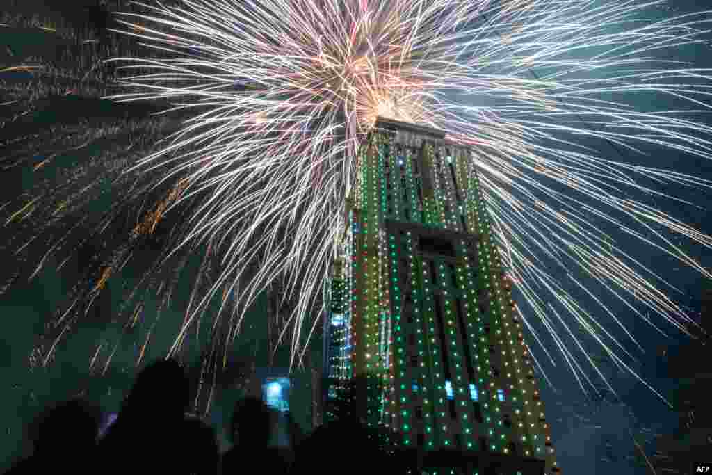 La gente mira el lanzamiento de fuegos artificiales desde el edificio de Old Mutual Tower para celebrar el año nuevo en Nairobi el 1 de enero de 2023. [AFP]