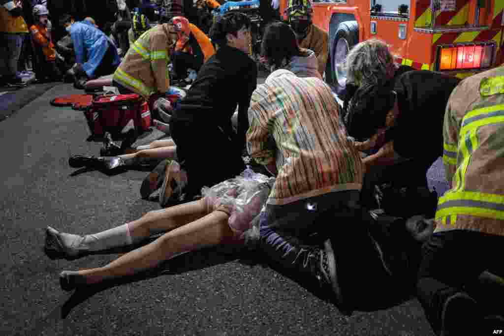 Emergency workers and others assist people who were caught in a Halloween stampede in the district of Itaewon in Seoul, South Korea, Oct. 29, 2022. More than 150 people have been killed in the stampede.