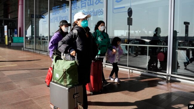 In this file photo, passengers are seen wearing masks as they walk through the Capital airport terminal in Beijing on Dec. 13, 2022. (AP Photo/Ng Han Guan, File)