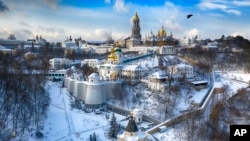 FILE - A bird flies over the sky near the 1,000-year old Orthodox Pechersk Lavra monastic complex (Monastery of Caves) in Kyiv, Ukraine, Jan. 15, 2021.