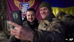 Un soldado ucraniano se toma una selfie con el presidente Volodymyr Zelenskyy (izq.), durante su visita a Sloviansk, región de Donbás, Ucrania, el martes 6 de diciembre de 2022. [Foto cedida por la Oficina de Prensa Presidencial de Ucrania]