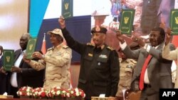 FILE: Sudan's Army chief Abdel Fattah al-Burhan (C R) and paramilitary commander Mohamed Hamdan Dagalo (C L) lift documents alongside civilian leaders following the signing of an initial deal in the capital Khartoum on December 5, 2022. 