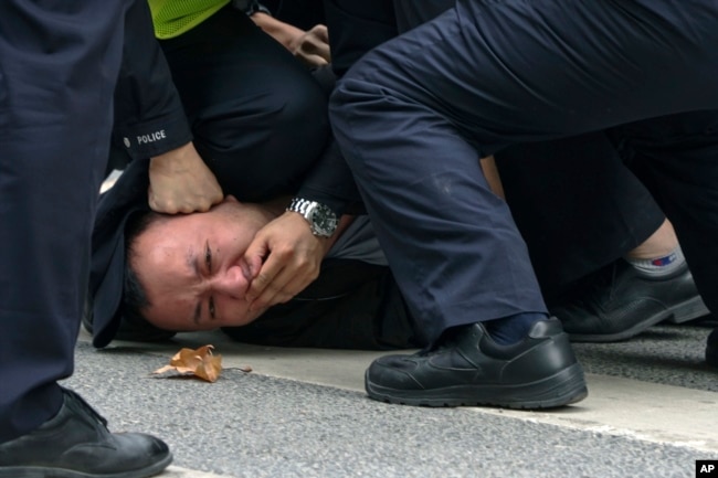 FILE - Policemen pin down and detain a protester during a protest on a street in Shanghai, China on Nov. 27, 2022. (AP Photo, File)