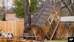 A greenhouse sits on a fence in the backyard of Randy Popiel's home after a possible tornado in Grapevine, Texas, Dec. 13, 2022.