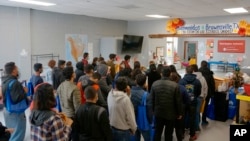 ARCHIVO - Varias personas hacen fila en el centro de bienvenida a migrantes frente a la estación de autobuses, el viernes 16 de diciembre de 2022, en Brownsville, Texas. 