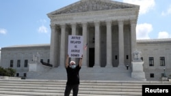 Демонстрант у здания Верховного суда держит в руках плакат с надписью «Отложенное правосудие – это отказ в правосудии». В июле 2020 года Верховный суд постановил, что прокурор штата Нью-Йорк имеет право на ознакомление с налоговыми декларациями Трампа