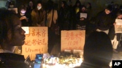 In this photo obtained by The Associated Press, demonstrators stand by protest signs in Shanghai, Nov. 26, 2022. 