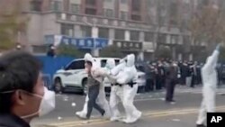 FILE: security personnel in protective clothing were seen taking away a person during protest at the factory compound operated by Foxconn Technology Group who runs the world's biggest Apple iPhone factory in Zhengzhou. Image provided November 23, 2022