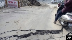 A motorist navigates his way through a crack on a road in Joshimath, India, Jan. 3, 2023.