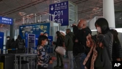 FILE - Passengers wearing face masks line up for a security check to enter a departure gate at Beijing Capital International Airport, in Beijing, China, Dec. 29, 2022.