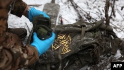 A Ukrainian Army medic unloads cartridges from the bag of a wounded soldier on a roadside not far from Soledar, Donetsk region, Jan. 14, 2023.