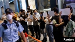 香港市民手持白纸和花束悼念新疆火灾死难者，支持中国内地的抗议活动。香港警察前去查看他们的身份证。（2022年11月28日）