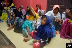 Ethnic Rohingya women and children sit on the floor upon arrival at a temporary shelter after their boat landed in Pidie, Aceh province, Indonesia, Dec. 26, 2022.