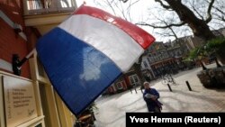 Seorang perempuan berjalan melewati bendera nasional, sehari sebelum pemilihan umum, di Delft, Belanda, 14 Maret 2017. (Foto: REUTERS/Yves Herman)