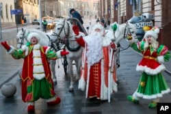 Seorang aktor berpakaian seperti Ded Moroz (Santa Claus) atau Pastor Frost, dan aktor lainnya menyapa anak-anak saat mereka tiba di Toko Anak Pusat di Moskow, Rusia, Minggu, 4 Desember 2022. (Sofia Sandurskaya, foto Kantor Berita Moskow melalui AP)