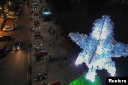 Pohon Natal yang terbuat dari botol plastik dan patung planet Bumi yang terbuat dari tutup botol air di Bnachii, Lebanon, 16 Desember 2022. (REUTERS/Issam Abdallah)